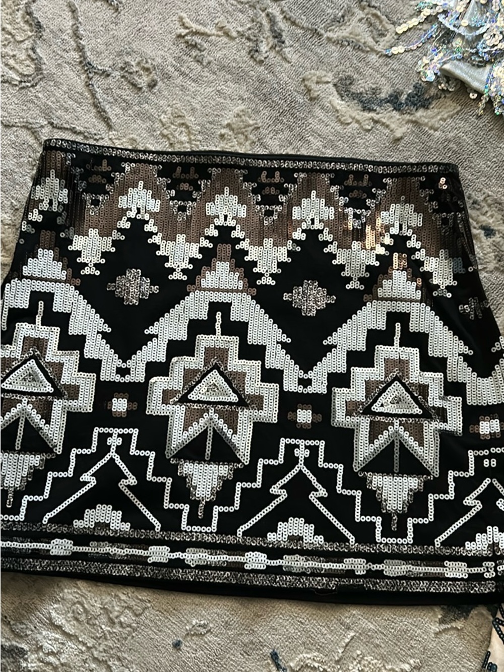 Express mini skirt features a bold black, silver, and gold Aztec